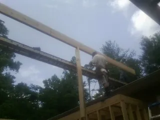 Carpenter setting a ridge beam over a new addition frame — Ice Dam Removal by Roofing Brothers in Watsontown