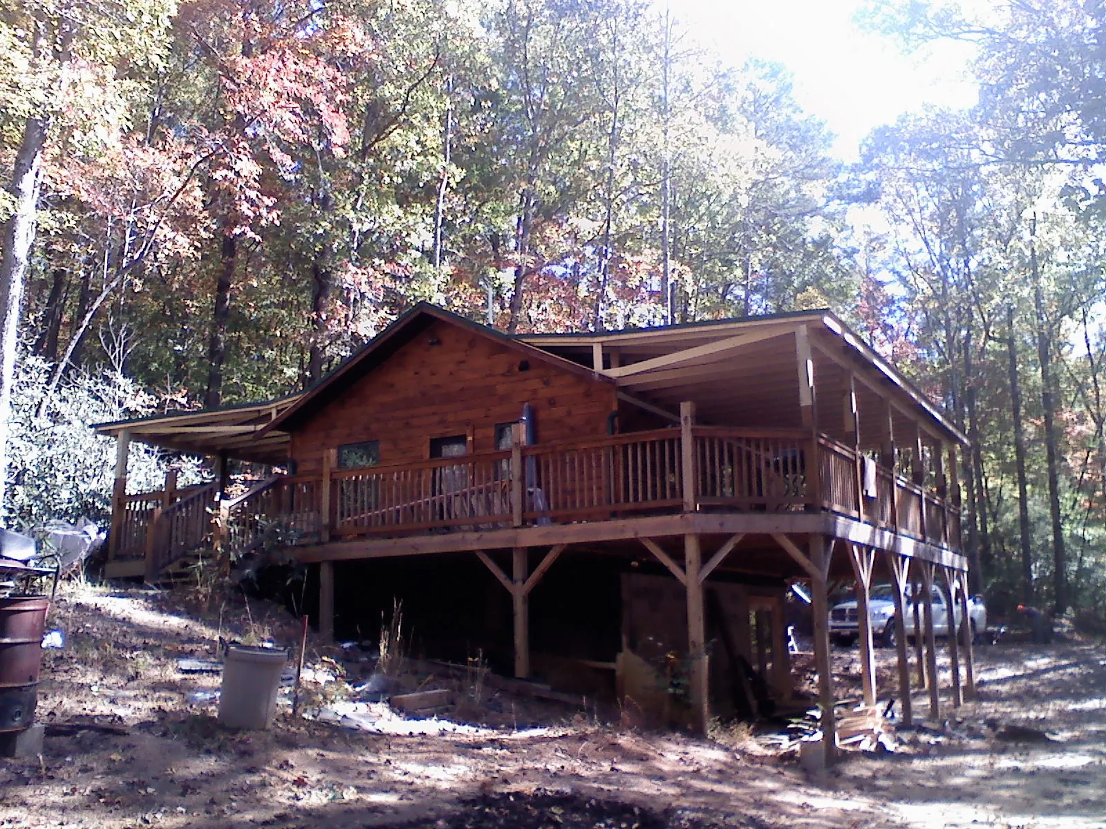 Log cabin with a wraparound porch and metal roof in the fall in Watsontown