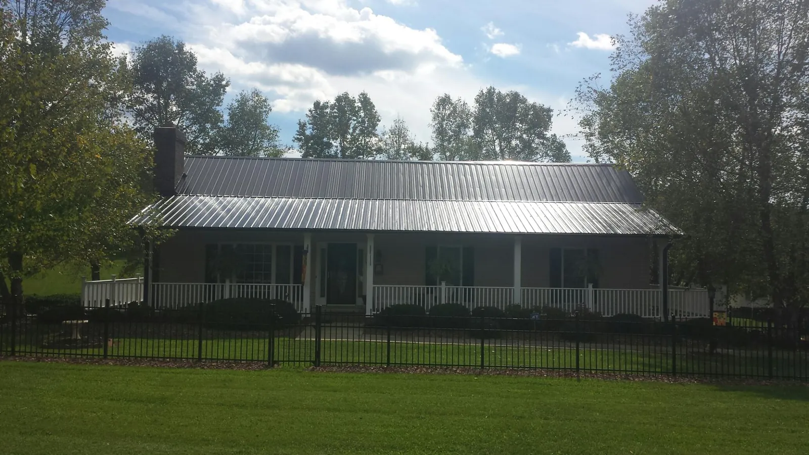 Gray metal roof on a brick ranch with a full width front porch — Gutter Guard Installation work by our crew in Watsontown