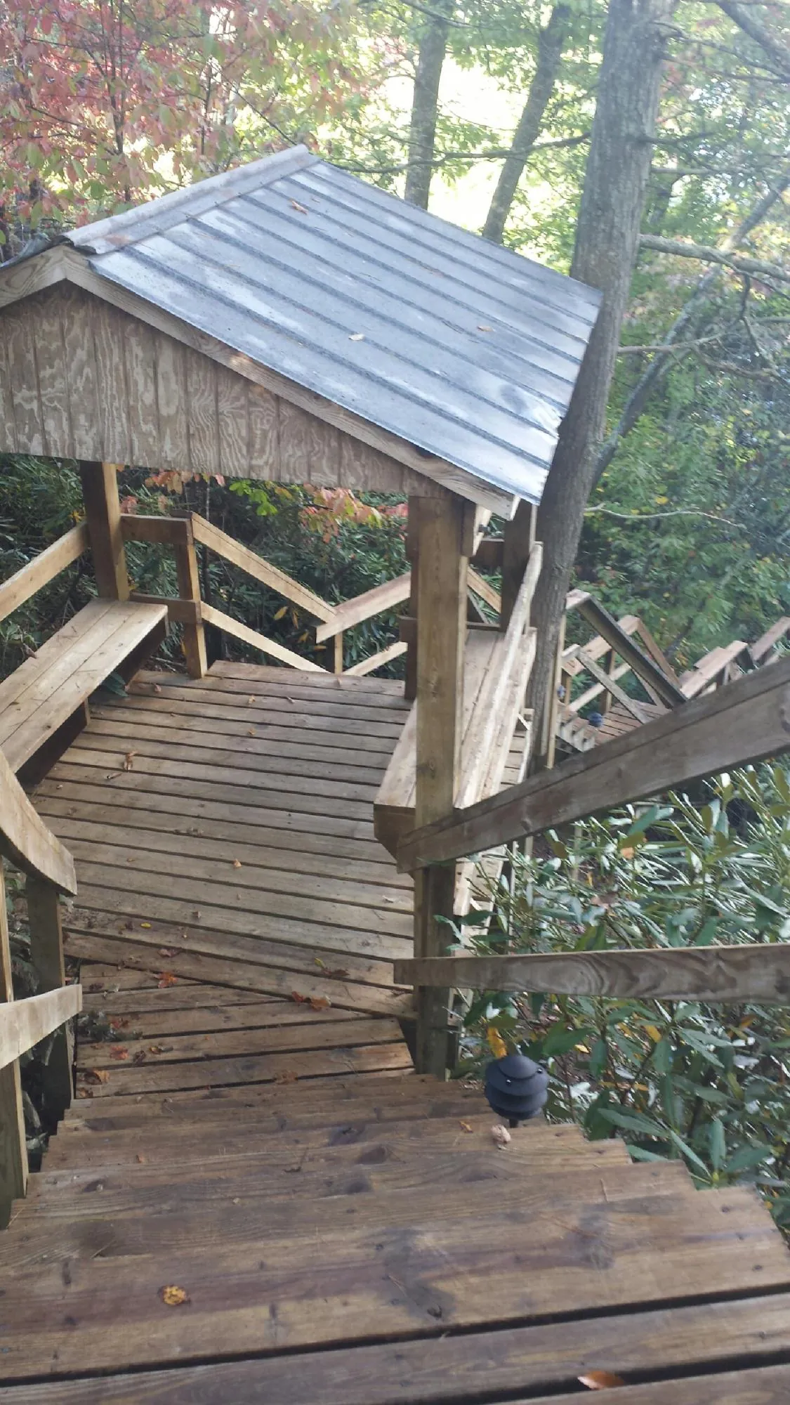 Metal roofed shelter over wooden steps on a wooded walkway — Skylight Repair & Installation work by our crew in Watsontown