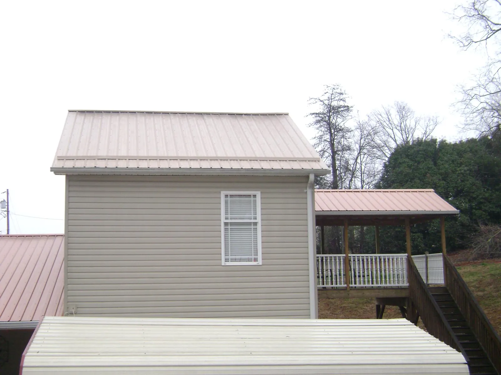Tan metal roofs on a two story addition and attached porch, from a Roof Replacement job in Watsontown