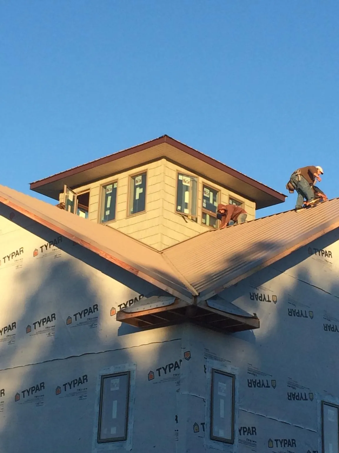 Roofers working around a rooftop cupola on a new metal roof at sunset — Roof Waterproofing in Watsontown by Roofing Brothers